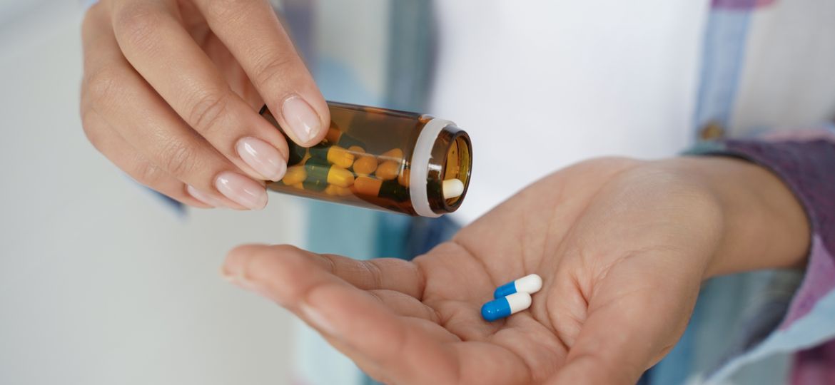 Female holding pills in palm, taking dietary supplements, vitamins or medicine, closeup. Health care