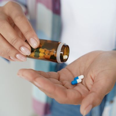 Female holding pills in palm, taking dietary supplements, vitamins or medicine, closeup. Health care