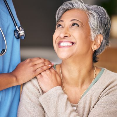 Nurse, senior woman and smile with comfort, holding hands or support in nursing home for retirement. Doctor, medic or caregiver with kindness, empathy or gratitude for help, trust or service in house