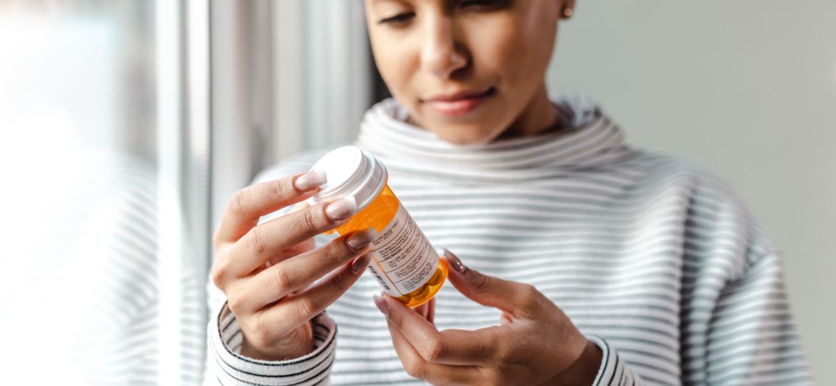 A serious young woman holding a bottle of medicines