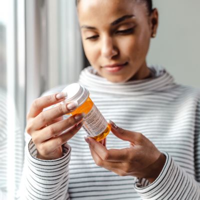 A serious young woman holding a bottle of medicines